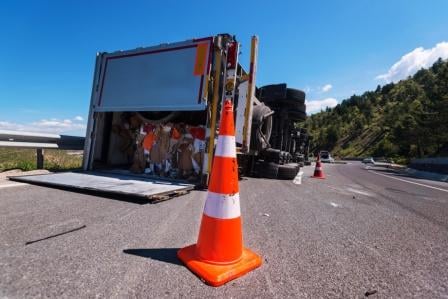 crashed semi truck lying on its side on the sholder of the highway