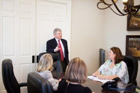 Gary Bruce standing in law office conference room speaking to staff