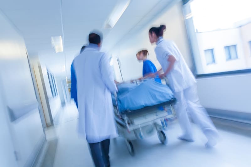 Hospital staff rushing down hall with patient on a gurney after a medical malpractice error