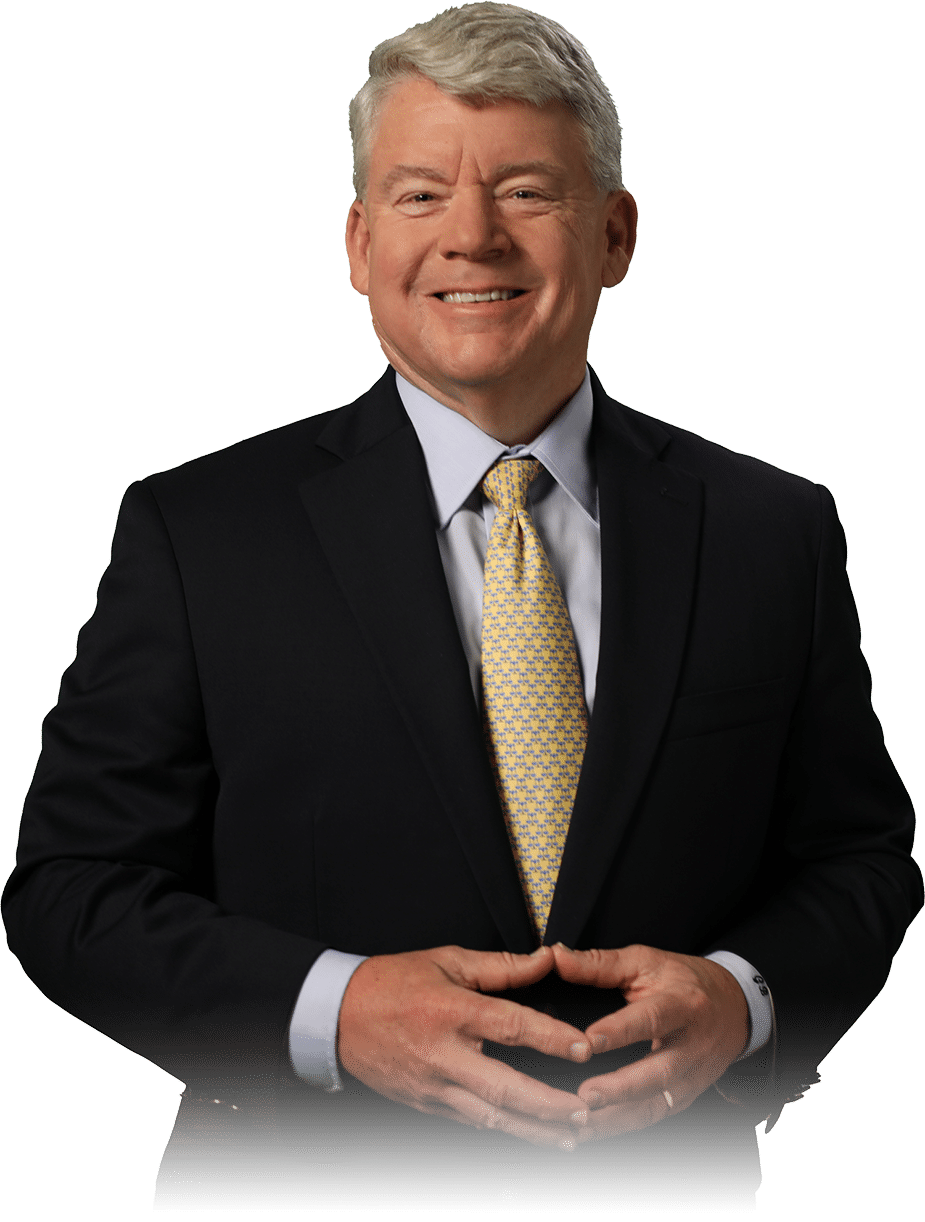 Smiling man in a suit with a yellow tie standing against a plain background.